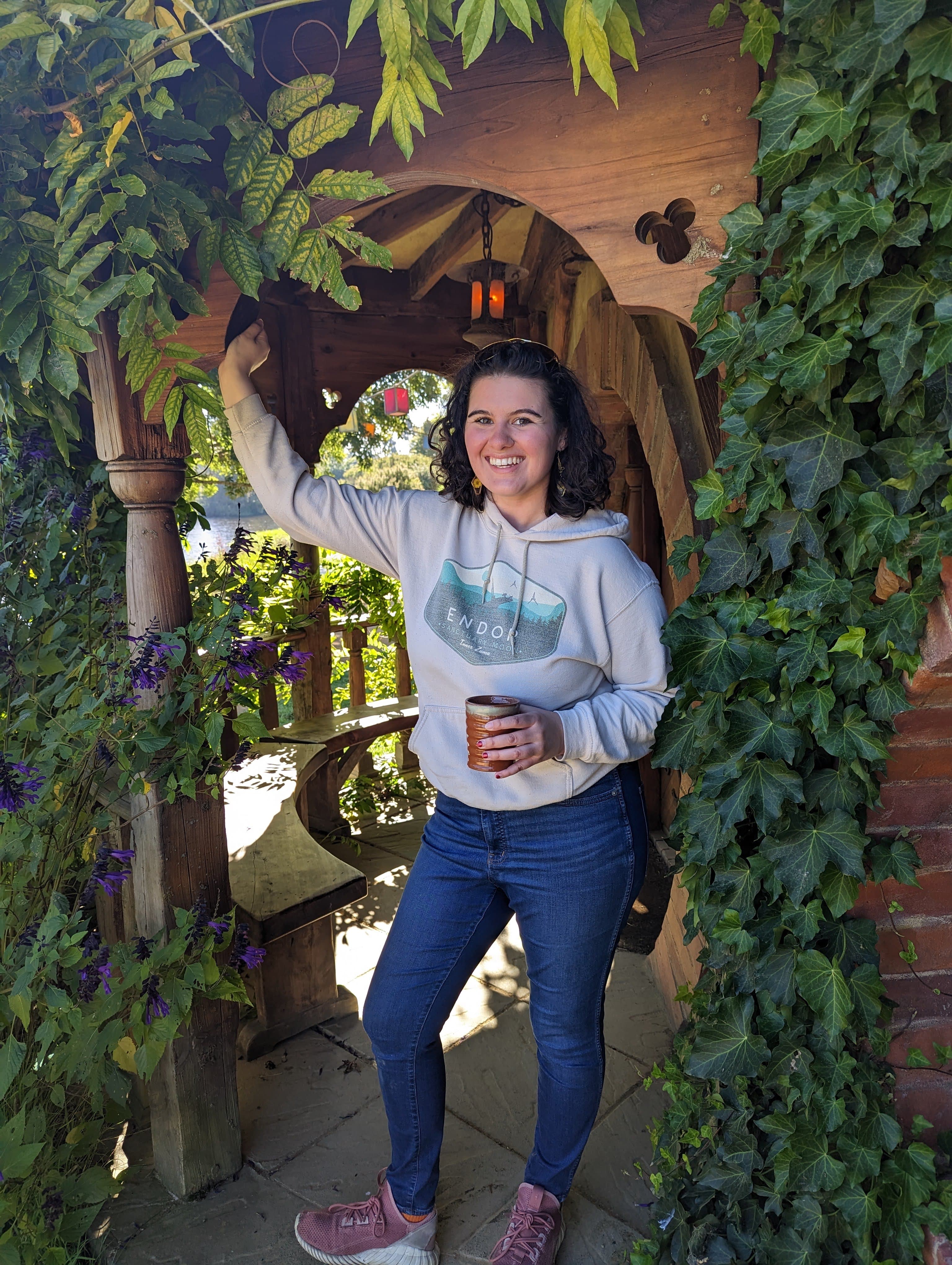 Selena standing in front of a wooden archway with flowers